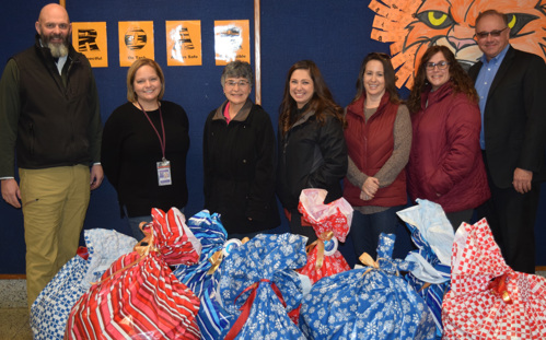 United Bank Limited employees and school officials stand with bags of coat donations